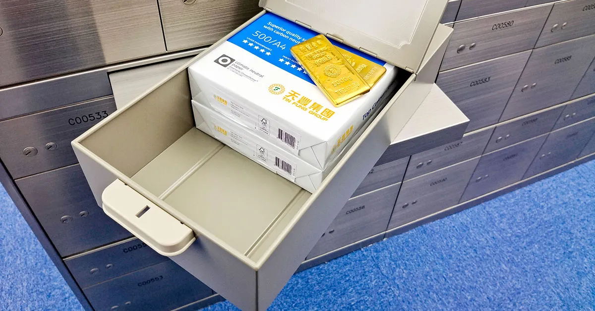an open safe contains gold bars and printer paper